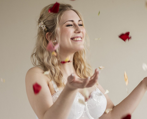 Frau in Hochzeitsmieder, die Rosenblätter in die Luft wirft