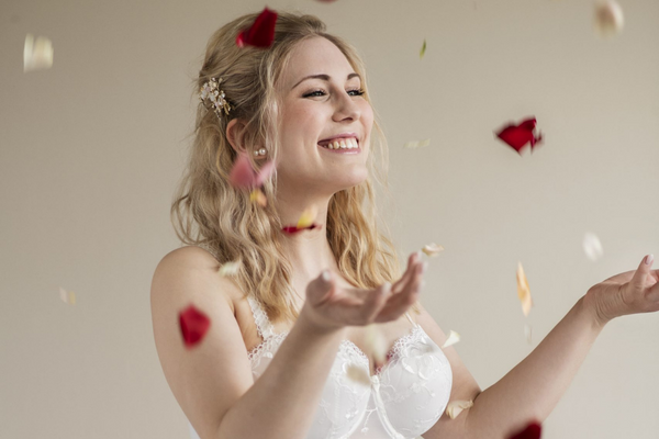 Frau in Hochzeitsmieder, die Rosenblätter in die Luft wirft